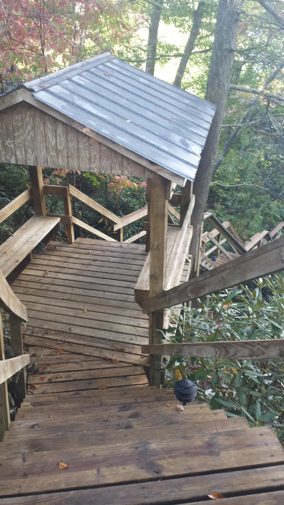 Metal roofed shelter over wooden steps on a wooded walkway — Skylight Repair & Installation work by our crew in Baltic